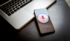 Speech recognition concept - close-up mobile phone with siri microphone icon and wave sound symbol. Personal voice assistant, deep learning application on smartphone screen.