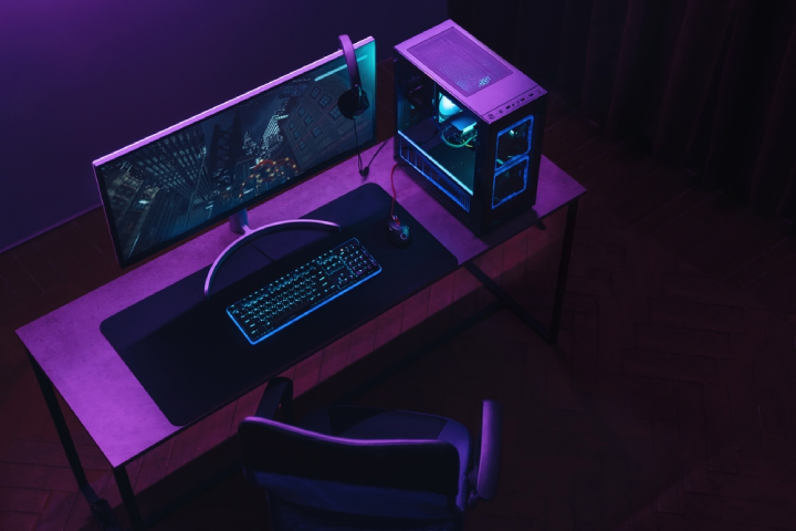 Top view of gamer work space and professional gaming setup: mouse, keyboard, monitor, headset, powerful computer. Premium PC with RGB light inside.