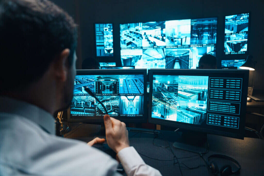Police advanced technologies: A police officer sits at a desk looking at CCTV screens.