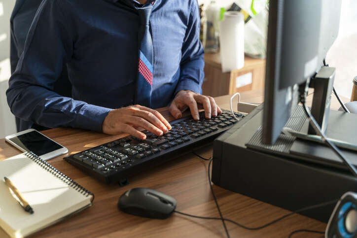 A civil servant is typing at his desk. 