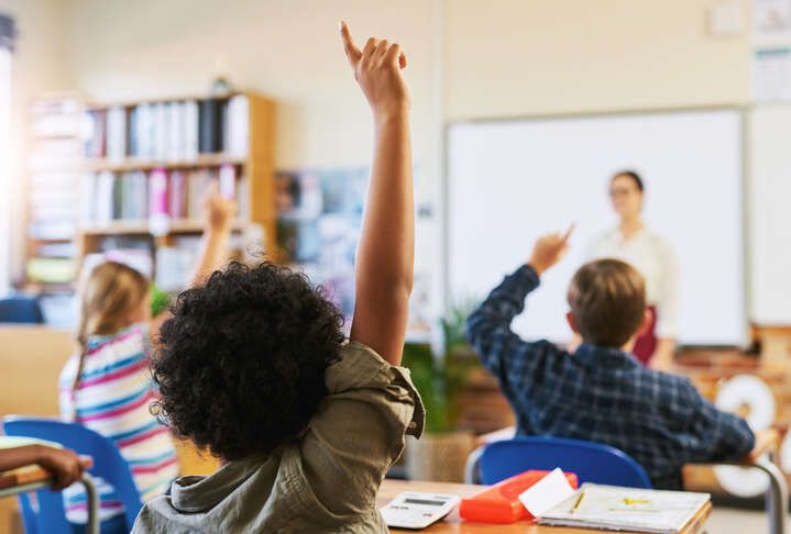 Shot of an unrecognisable group of children sitting in their school classroom and raising their hands to answer a question - stock photo