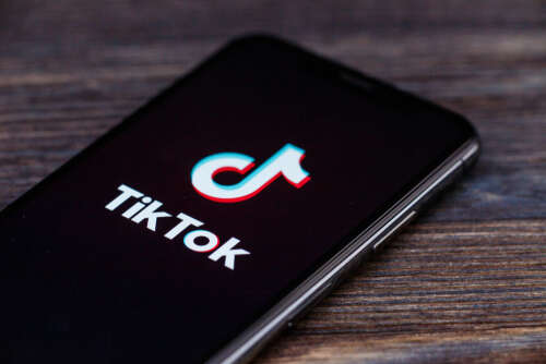TikTok logo on a smartphone, laying on a table. 