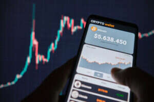 An image of a stocks graph in the background with a smartphone showing a crypto wallet.
