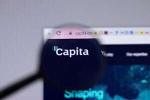 Image shows Capita logo on a web browser through magnifying glass.