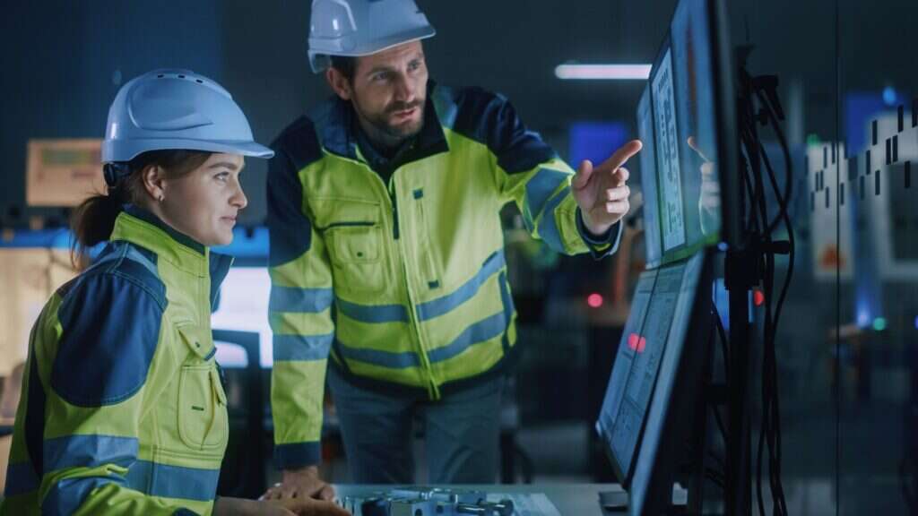 Staff in hard hats and high-visibility uniforms working with the assistance of AI. 