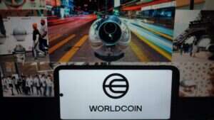 An image of Worldcoin's patented orb-like iris scanner, foregrounded by a smartphone bearing the Worldcoin logo.