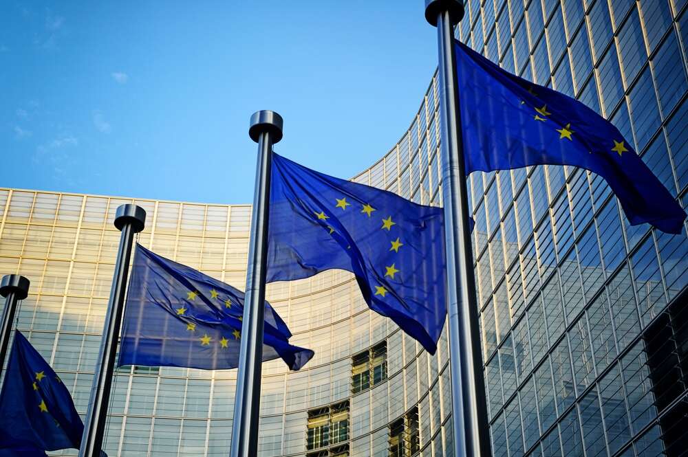 EU flags flutter outside the European Commission building, in a photo illustrating an article about the imminent passage of the EU AI Act.