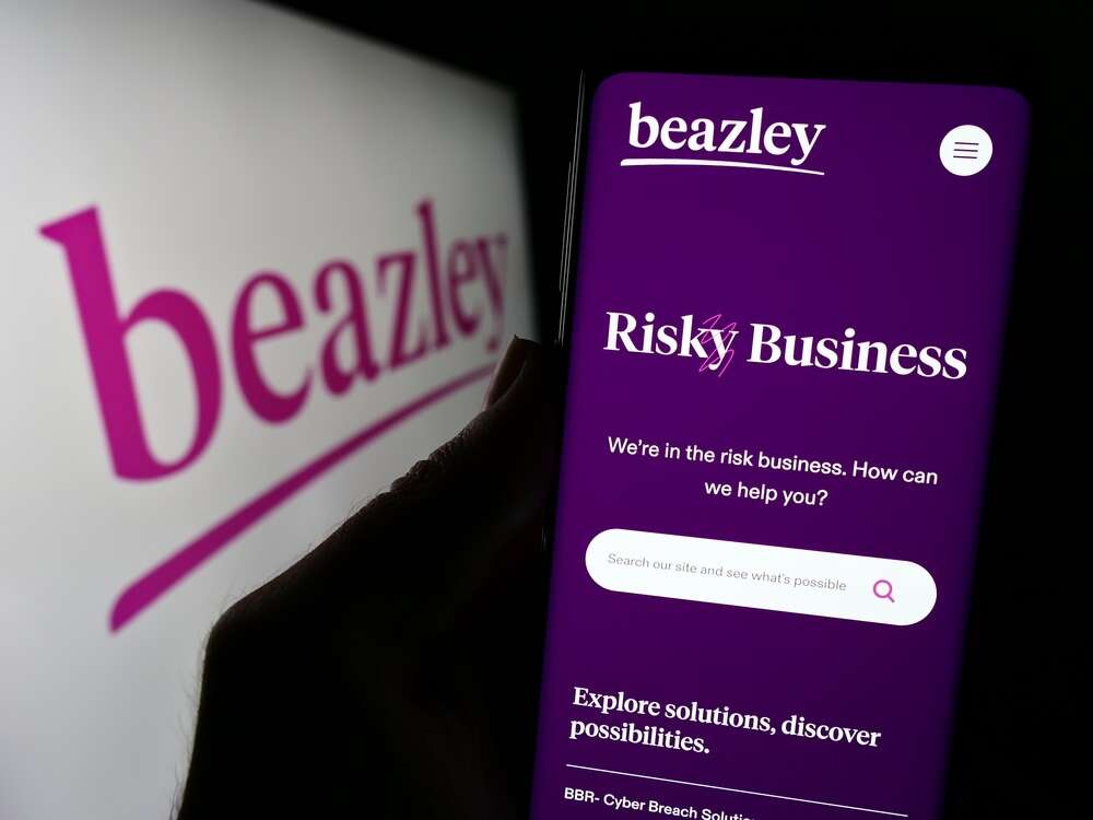 Person holding cellphone with webpage of British insurance company Beazley plc in front of business logo. Beazley has recently completed a $140 million catastrophe bond.