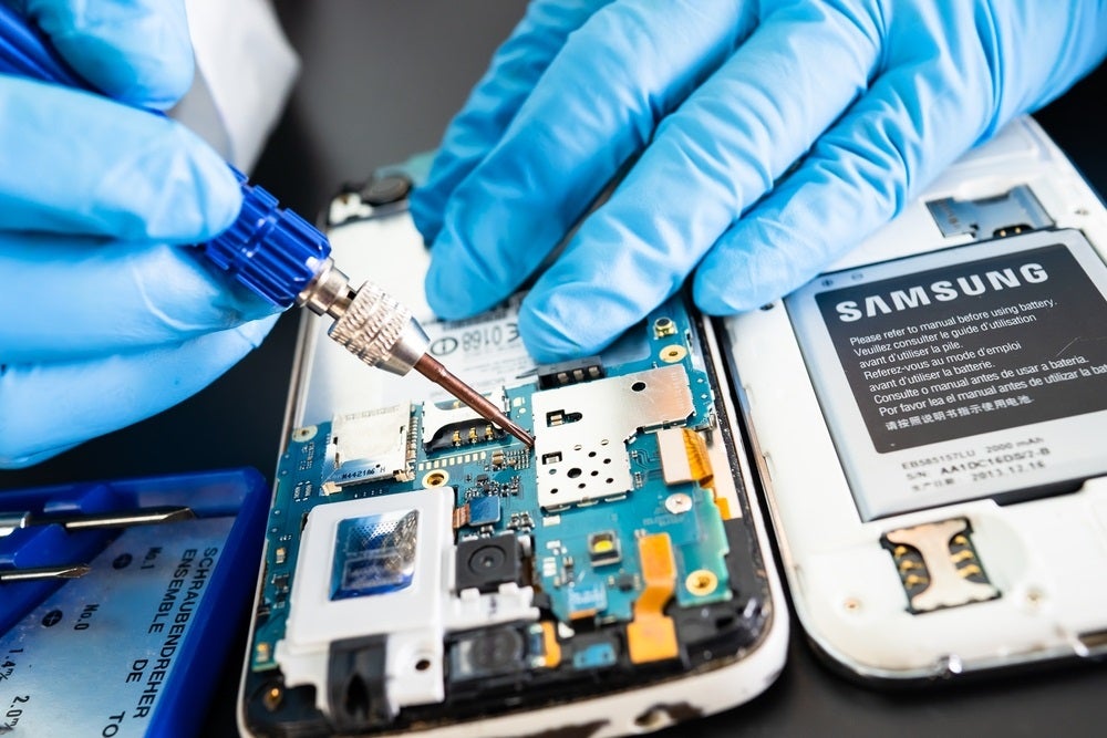 A photo of a Samsung worker soldering a chip into a phone, used to illustrate a story about a union threatening a new Samsung strike.